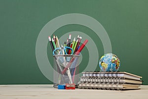 Back to school template with stationeries and books on table over green