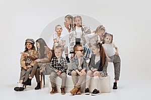Ten happy smiling kids, little girls and boys in modern outfits posing on grey studio background. Beauty, kids fashion