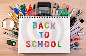 Back to school text on notebook over school supplies or office s