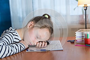 Back to school. Tired little child girl sleeping on the desk while doing homework. Education learning concept