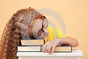 Back to school. Tired schoolgirl in glasses is sleeping on a books at desk, got tired from studying, fell asleep while