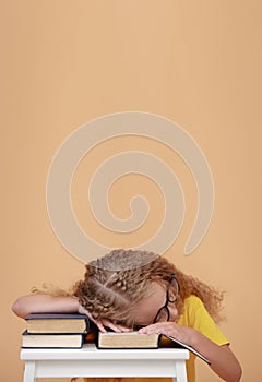 Back to school. Tired schoolgirl in glasses is sleeping on a books at desk, got tired from studying, fell asleep while