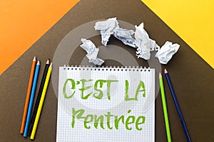 Back to school translated in french concept, notebook isolated on colorful paper background.