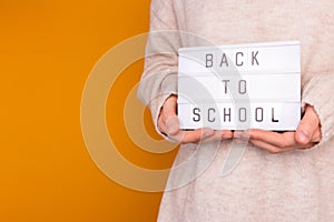 Back to school. Woman hold in hands lightbox with letters.