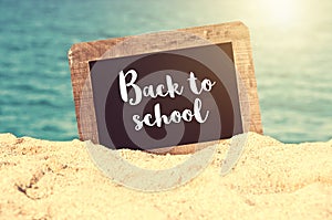 Back to school written on a vintage chalkboard in the sand of a beach