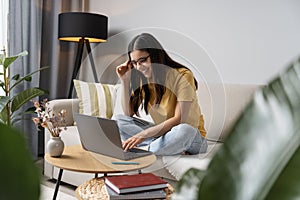 Back to study. Happy student doing her work at home on laptop in a cosy room