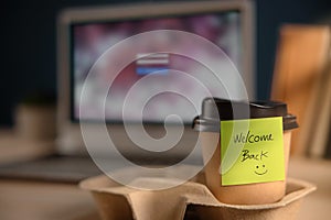 Back to Work Concept. Closeup of Welcome Note on Takeaway Coffee Cup in Office Desk