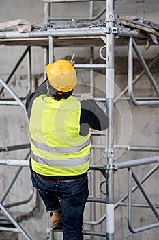 Back turned construction worker climbing a ladder photo