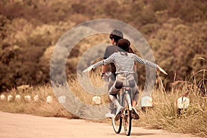 Back veiw of young couple of hipsters riding a bicycle together