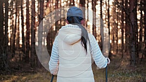 Back view active woman enjoying scandinavian walking at natural forest. pine Dragon RED camera