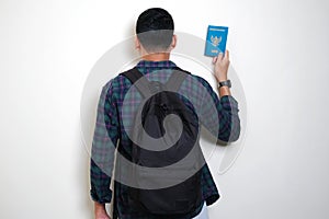 Back view of Adult Asian man wearing backpack showing Indonesia passport ready for travelling