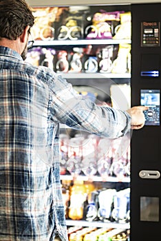 Back view of adult mature man choosing snacks and drinks on 24h free automated distributor - people buying food on airport gate -