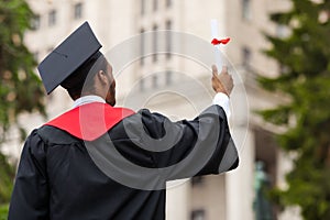 Back view of african american guy in graduation costume