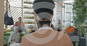 Back view of African American lady talking to people diverse group in modern coworking place