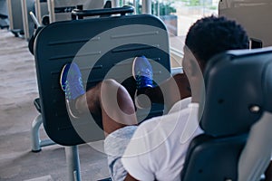 Back view of African American man doing exercise on leg press during fitness training in modern gym