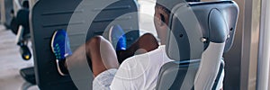 Back view of African American man doing exercise on leg press during fitness training in modern gym