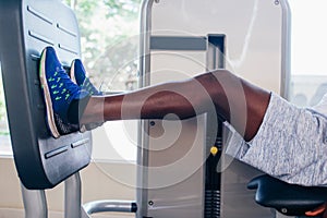 Back view of African American man doing exercise on leg press during fitness training in modern gym