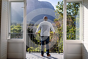 Back view of african american senior man standing on balcony and looking into distance