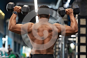 Back view of african american shirtless man exercising at gym