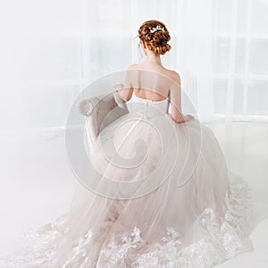 Back view of amazing young bride. Red head woman seat on the chair. Elegant hairstyle.