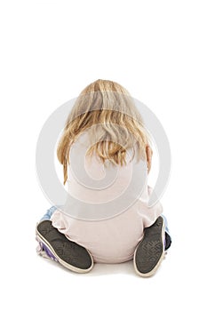 Back view of angry little girl with folded hand, sitting on knees