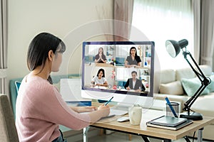 Back view of Asian business woman talking to her colleagues about plan in video conference. Multiethnic business team using