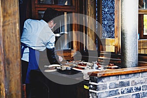 Back view of Asian chef with a mask and apron in restaurant kitchen