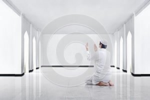 Back view of asian muslim man kneeling and praying to god