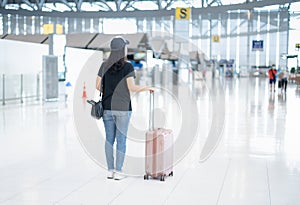 The back view of Asian woman carrying luggage suitcase and wearing surgicak mask prepare to check-in for get the ticket boarding