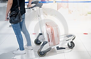 The back view of Asian woman carrying luggage suitcase and wearing surgical mask prepare to check-in for get the ticket boarding