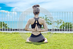 Back of view Asian woman relaxing in yoga Shoulder Opening Pose with beautiful sea