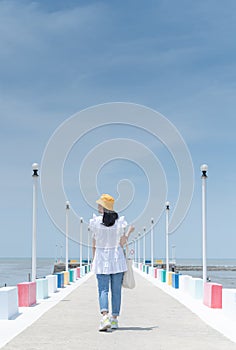 The back view of asian woman walking on the rainbow bridge to see the viewpoint at the Samut Sakorn province, one of the province