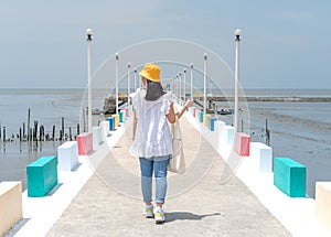 The back view of asian woman walking on the rainbow bridge to see the viewpoint at the Samut Sakorn province, one of the province