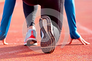 Back view of an athlete getting ready for the race on a running track. Focus on shoe of an athlete about to start a race