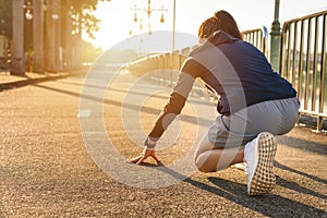 Back view of athlete runner woman in start position ready for sprint or running.