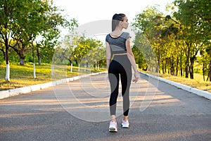 Back view of athlete runner woman in the summer city park.