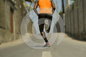 Back view of athletic black African American professional sport man running training hard outdoors on asphalt road during jogging