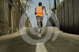 Back view of athletic black African American professional sport man running training hard outdoors on asphalt road during jogging