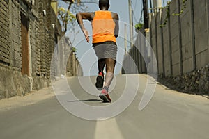 Back view of athletic black afro American professional sport man running training hard outdoors on asphalt road during jogging