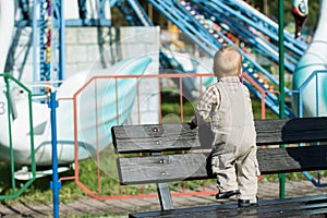 Back view of baby looking at carousel in attractions park