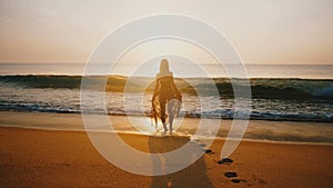 Back view backlight shot of happy young woman watching epic sunset on golden tropical ocean beach, concept of travel.