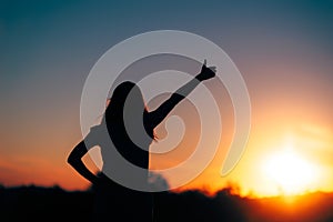 Back View Backlit silhouette of a Woman Holding Thumbs Up