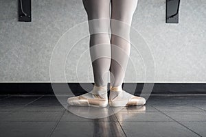 Back view of ballet dancer ballerina at the barre in dance class standing in first position