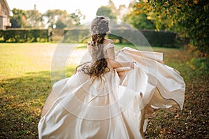 Back view of beautiful bride spinning in a wedding dress dancing on the green field