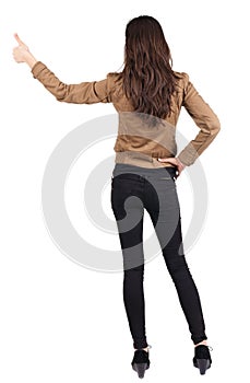 Back view of of beautiful brunette woman in brown jacket makes