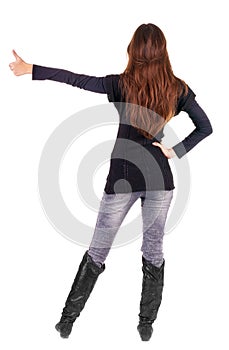 Back view of of beautiful brunette woman in jeans going thumb up