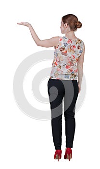 Back view of Beautiful business woman in suite looking at wall and Holds hand up.