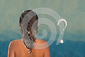 Back view of beautiful naked young woman taking shower in shower cabin. Soap question mark on shower cabin in the bathroom.