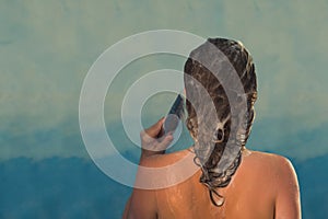 Back view of beautiful naked young woman taking shower in shower cabin.