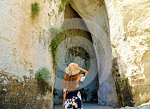 Back view of beautiful woman comes into the Ear of Dionysius Orecchio di Dionisio in Syracuse, Sicily, Italy photo